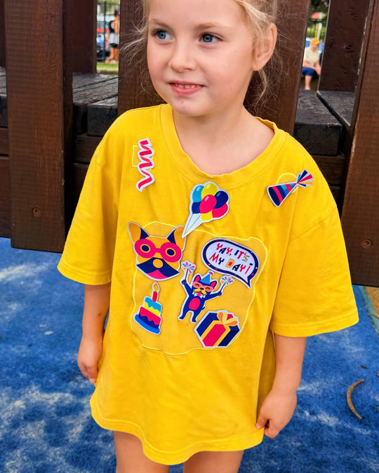 girl wearing yellow TeeBoo™ interactive kids T-shirts with Yay, It's My Day! BooPatch™ gift-ready sensory play set.