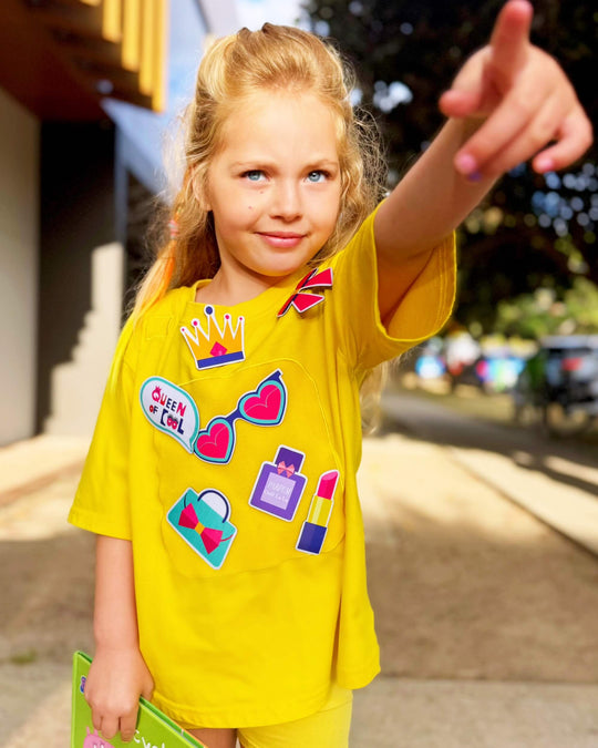 Girl playing in a yellow TeeBoo™ interactive kids T-shirt with the Queen of Cool BooPatch™ set for creative screen-free play.