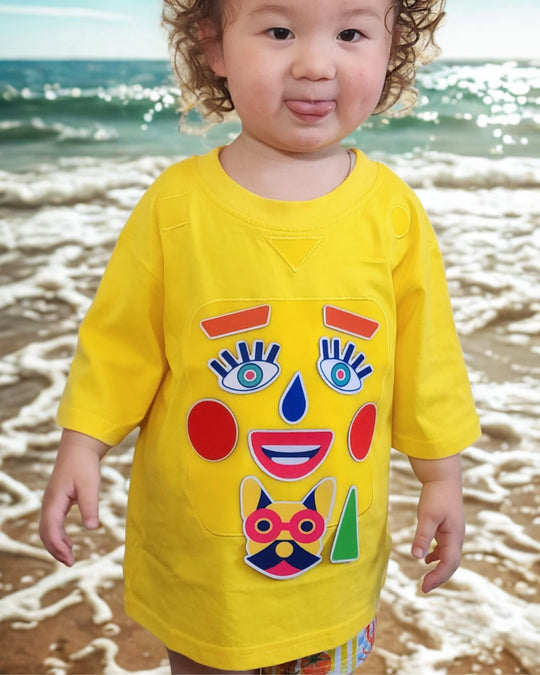 Child wearing a yellow TeeBoo™ interactive kids T-shirt with the Moody Friends BooPatch™ set at the beach.