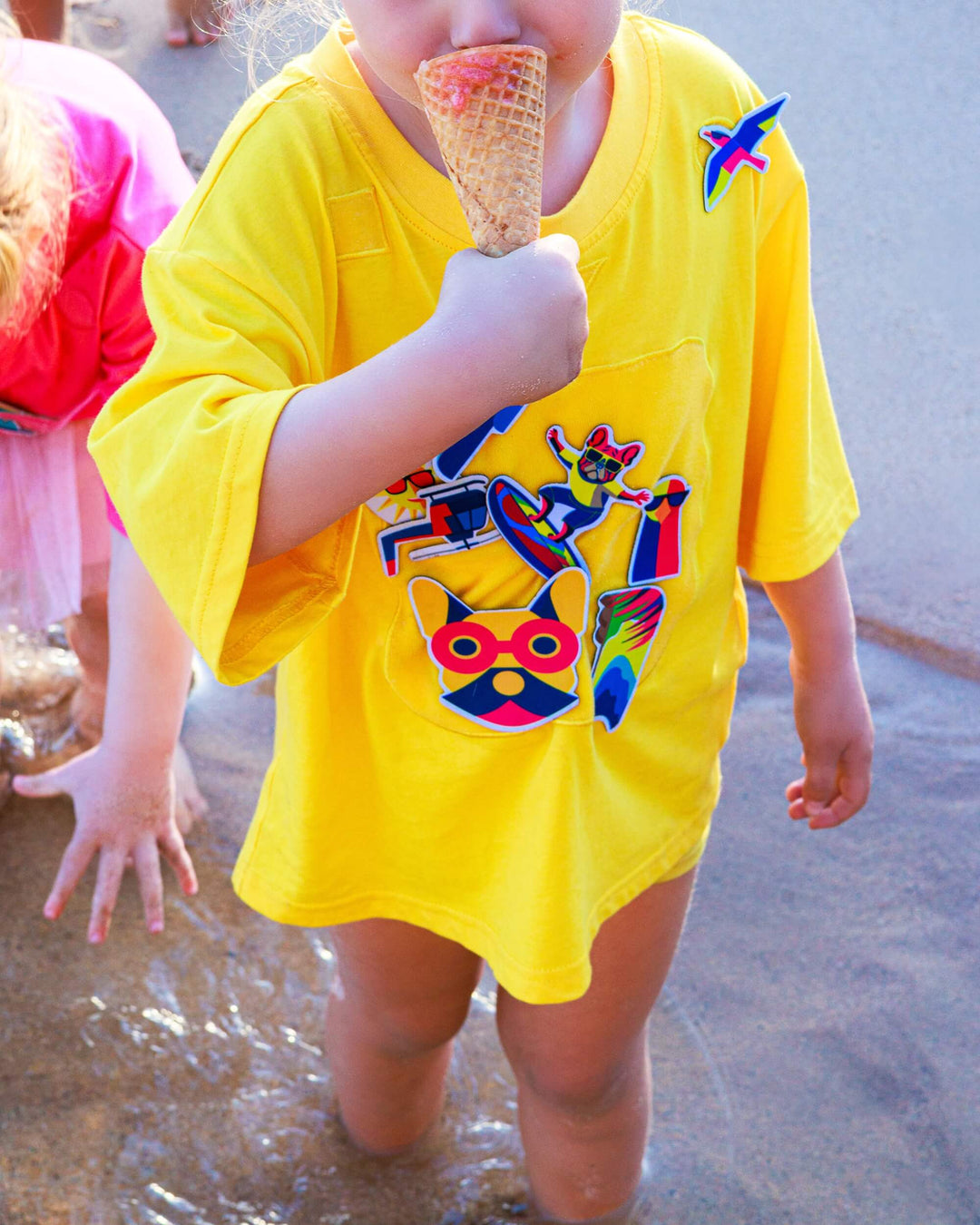 Child wearing yellow TeeBoo™ interactive kids T-shirt with Sun.Fun.Surf. BooPatch™ set during outdoor play.