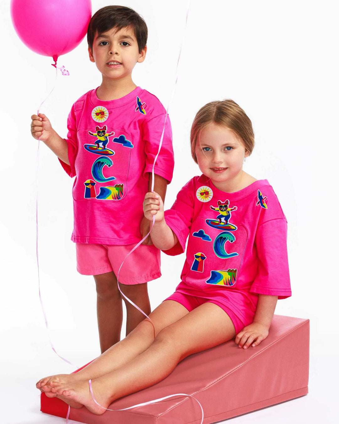 Boy and girl wearing pink TeeBoo™ interactive kids T-shirts with Sun.Fun.Surf. BooPatch™ premium gift-ready set.