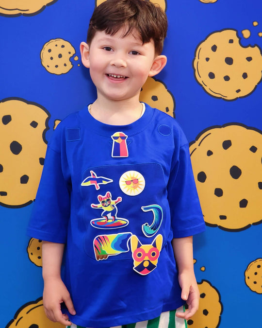 Child wearing blue TeeBoo™ interactive kids T-shirt with Sun.Fun.Surf. BooPatch™ set for creative sensory play.