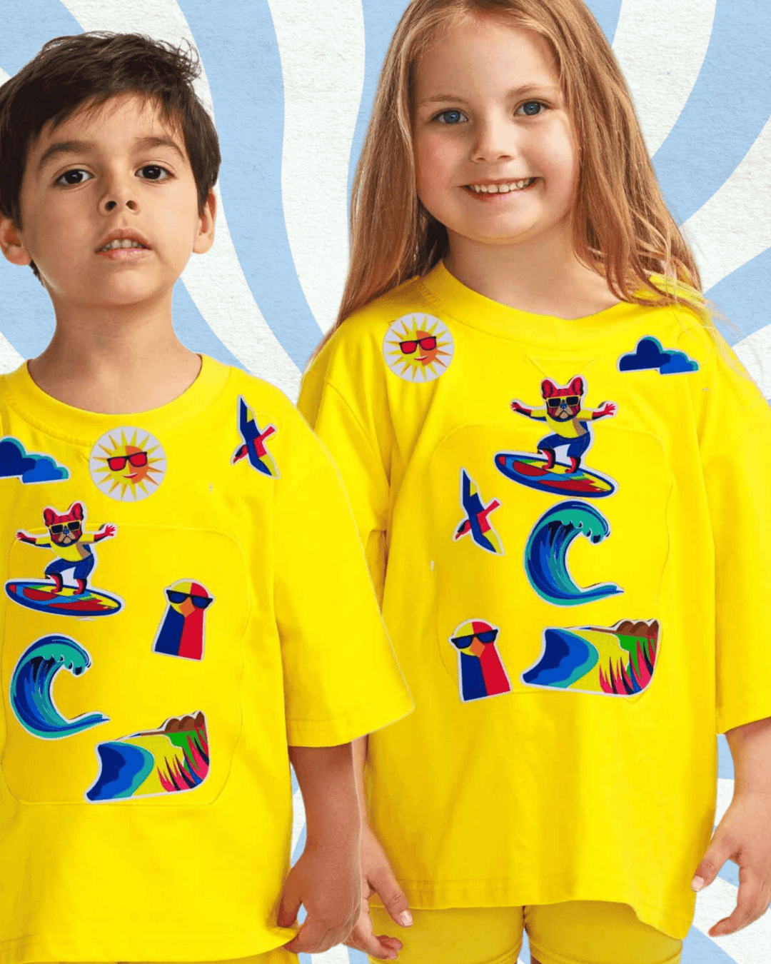 Boy and girl are wearing a yellow organic cotton TeeBoo™ interactive T-shirt with the Sun Fun Surf BooPatch™ set, including reusable beach and surfing patches for imaginative, screen-free play.