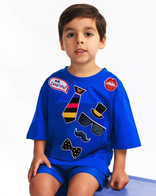 Boy wearing a blue TeeBoo™ interactive kids T-shirt with the Mr. Confident BooPatch™ gift-ready set.